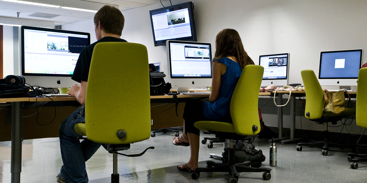 two students sitting at computers in the multimedia center
