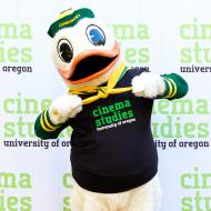 UO Duck Mascot wearing a t-shirt that says Cinema Studies